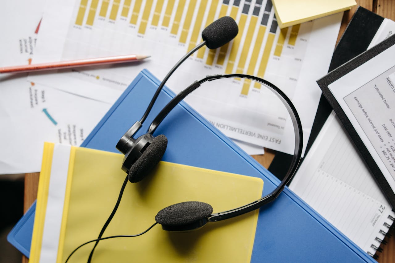 creative-02 Close-up of an office desk with headset, charts, and documents showcasing customer service support.