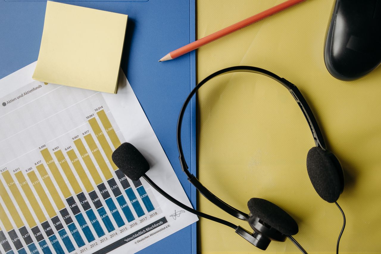 creative-02 A flat lay image depicting an office desk with a headset, chart, and stationery for business use.