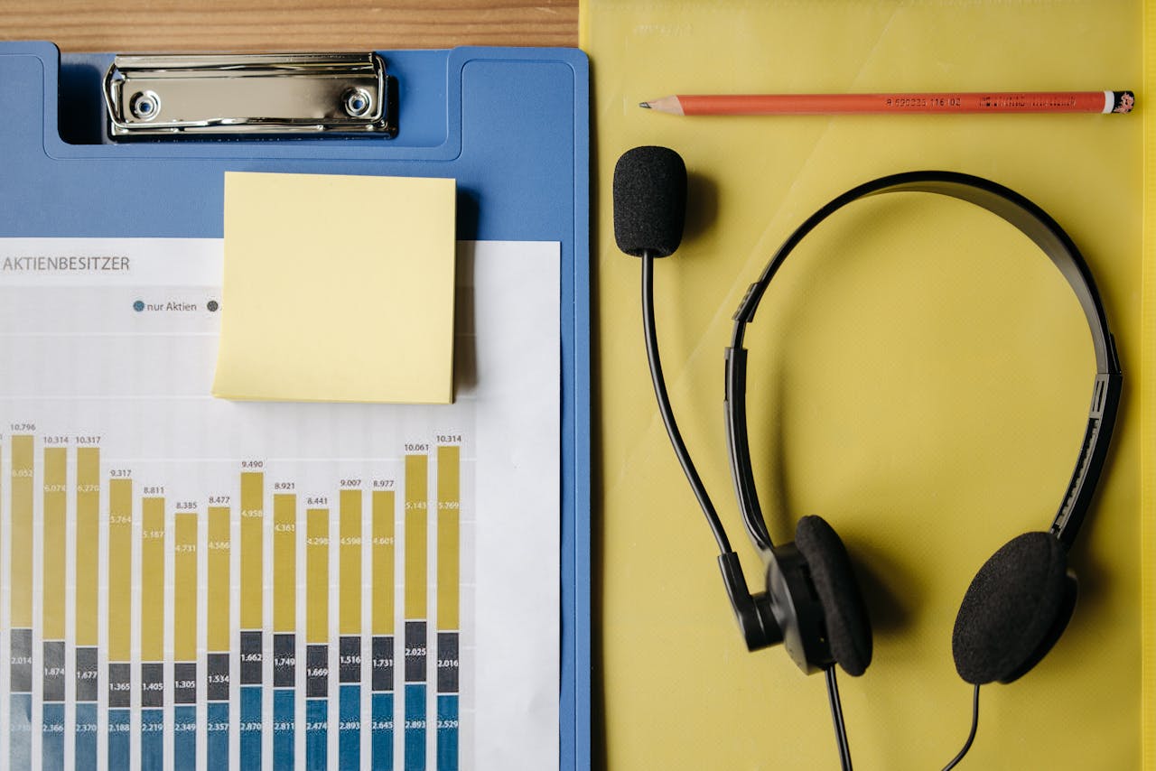 creative-03 Flat lay of office items including a graph, headset, and stationery on a desk.