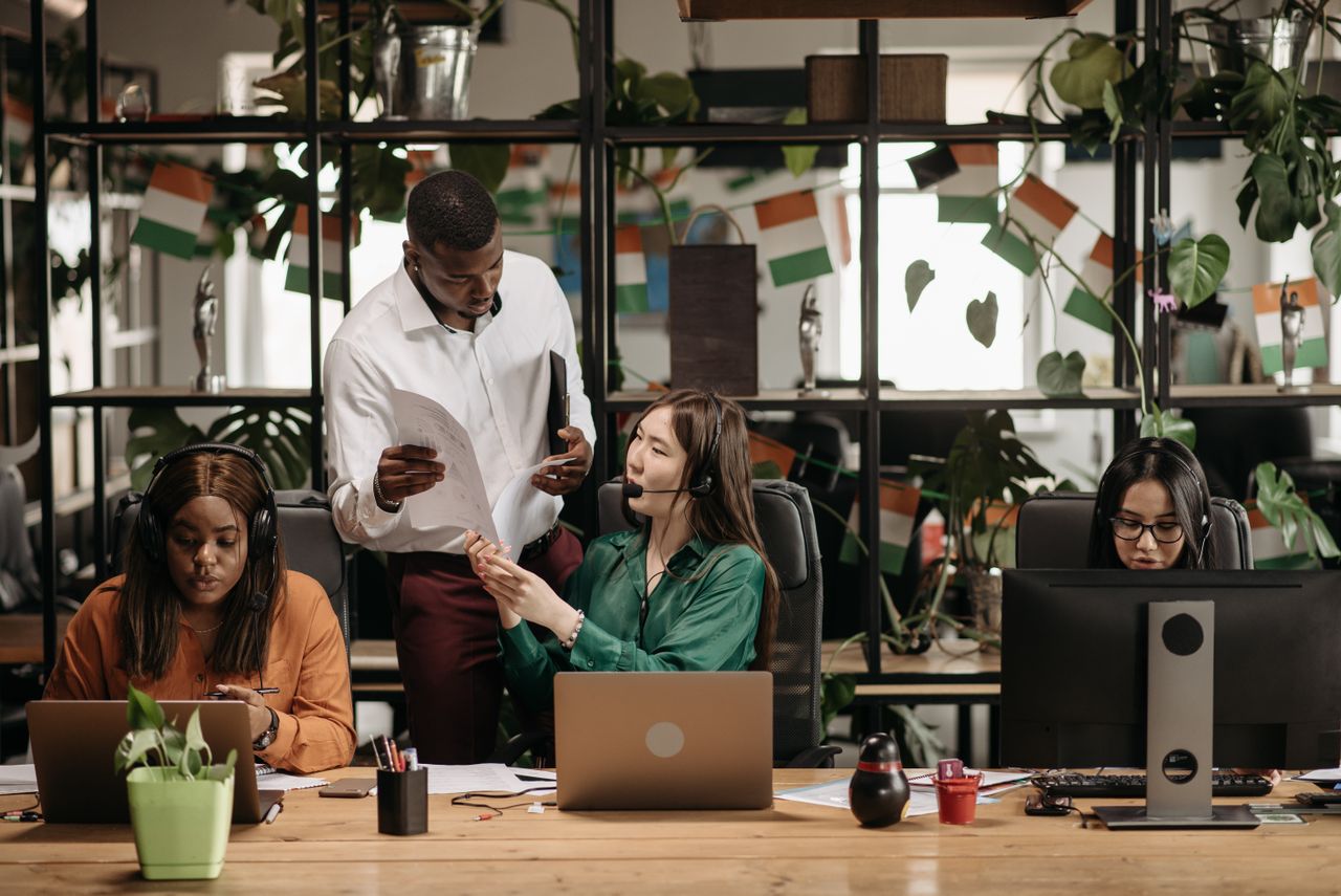 brand-01 A diverse group of colleagues collaborating in a modern office environment with plants and technology.