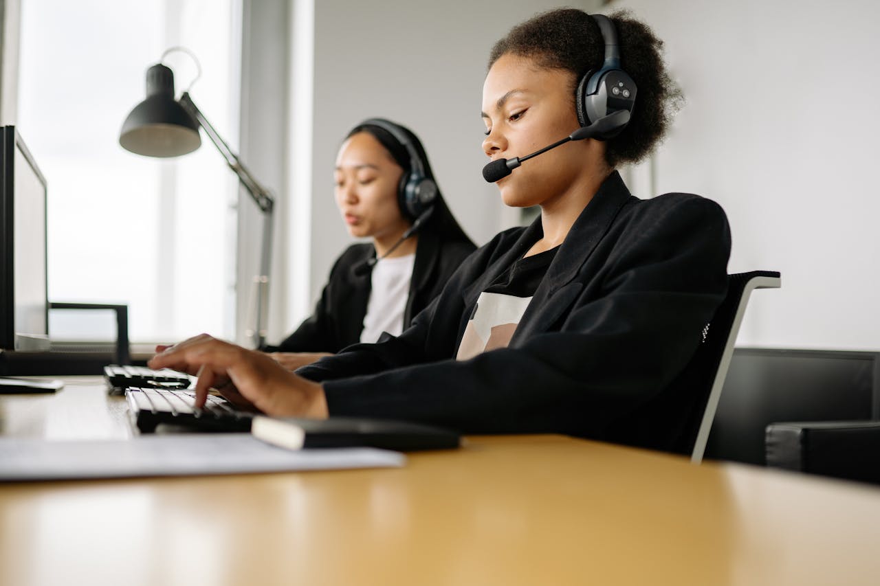 mobile-01 Two call center agents working at desks in an office setting with headsets.